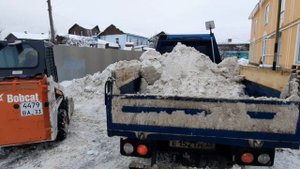 Погрузчик Bobcat 463 s70 загружает снегом самосвал.