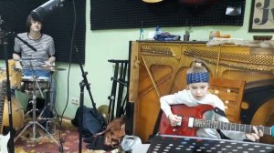 Репетиция музыкантов: супер-барабанщик и дети играют на электрогитаре