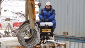 Разгрузка грузовика краном манипулятором зимой на стройке.