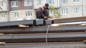 Экскаватор ждет пока Сварщик отрежет кусок металла, чтобы спустить его на землю.