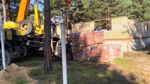 Автокран Ивановец КС-35715 на базе Маз подает рабочий кирпич на поддонах.