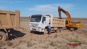 Погрузка песка экскаватором в самосвал на карьере в