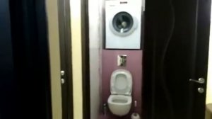 Стиральная машина установлена на верху в узком туалете