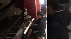 Мальчик играет на вокзале на фортепиано