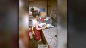 Маленькая девочка моет посуду.