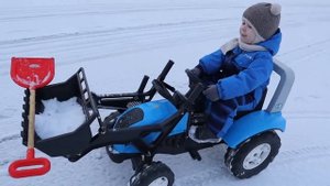 Малыш на синем тракторе с ковшом помогает папе и убирает снег