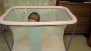 малыш стоит в манеже