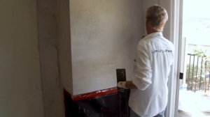 Plastering a colored cement stucco over fireplace.