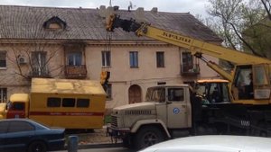 Автокран достаёт из ямы грузовик газовой службы. Трактор помогает