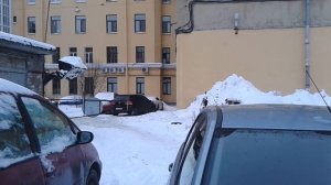 Трактор чистит снег во дворе.