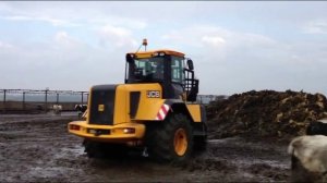 Фронтальный погрузчик JCB 434S разгребает навоз в коровнике