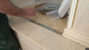 Укладка мозаики в мраморный пол.