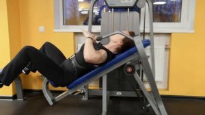 Жим в тренажере на дельты, лежа на спине