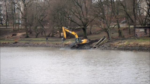 Экскаватор JCB работает на берегу озера Нижнее город Черняховск