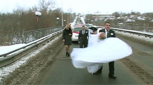 Жених несёт невесту на руках через мост, зимняя свадьба