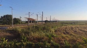 Железнодорожный переезд, пассажирский поезд, шлагбаум и грузовой поезд.