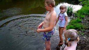 Дети ловят рыбу палкой, приманка маленькая рыбка. Fun fishing