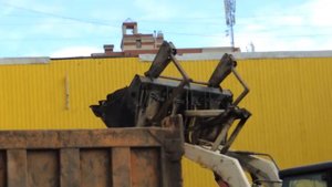 Белый экскаватор погрузчик загружает землю в Самосвал возле Магазина