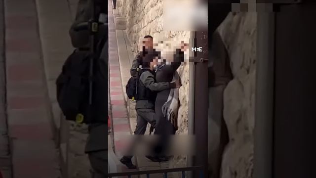 Israeli forces body search a Palestinian woman near Al-Aqsa Mosque