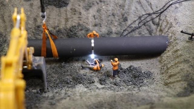 Сварщик варит трубу на макете