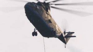 из-за леса взлетает огромный вертолёт Ми-26 с водосливным устройством