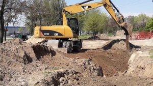 Экскаватор CATERPILLAR CAT M318D зарывает яму.