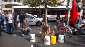 Уличный барабанщик виртуоз играет на пустых пластиковых ведрах.