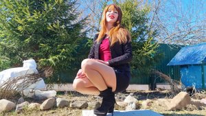 Рыжая длинноногая красотка в телесных колготках,  кожаной юбке и на каблуках танцует на природе