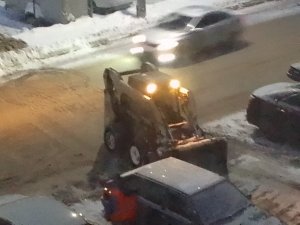 Минипогрузчик Бобкат убирает территорию от снега