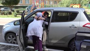 Пересаживание пациента с кресла-каталки в автомобиль.