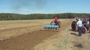 Трактор в поле пашет землю