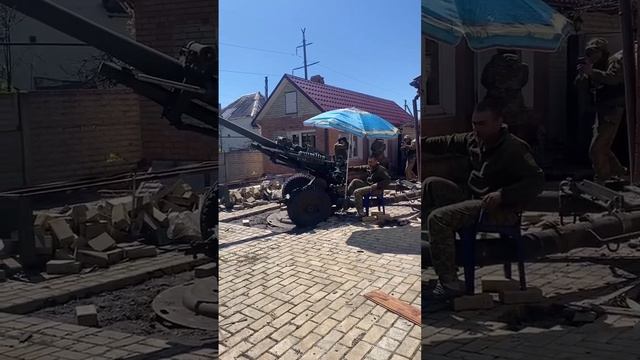 украинские боевики ведут огонь из артиллерии, сидя во дворе жилого дома под пляжным зонтом