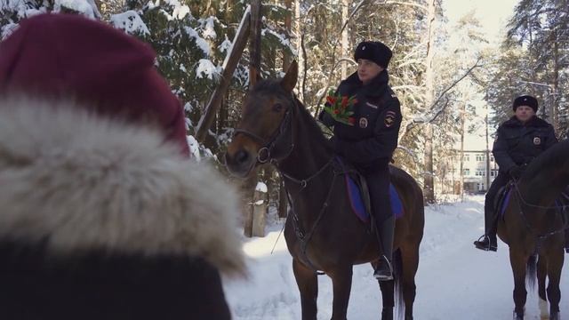 Верхом на конях и с цветами в руках.