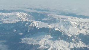 Авиаперелёт из Сочи в Москву. Вид на заснеженные горы Кавказа с борта самолёта.