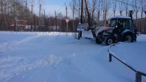 Экскаватор погрузчик чистит снег