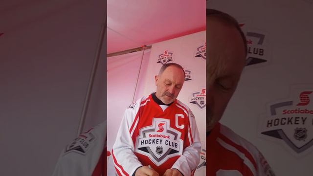 Bryan Trottier signs three hockey pucks for DAGR at Hometown Hockey in Enoch