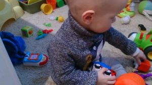 Годовалый малыш крутит колесо мусоровоз.