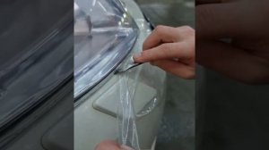 Мастер по детейлингу наносит бронеплёнку на фару от Nissan Teana.