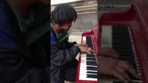 Бездомный играет на улице на пианино, песню которую он написал сам