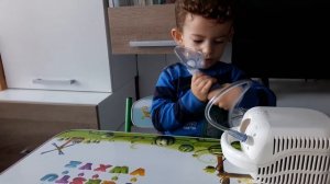 3 years old baby with flu enjoying self inhalation with nebulizer