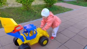 Малышка на синем тракторе играет на детской площадке