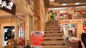 Клоун на ходулях по ступенькам Торгового центра