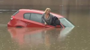 Женщина спасается от наводнения на крыше машины