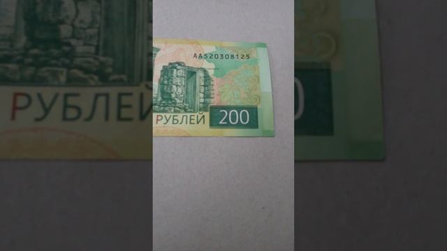 БАНКНОТА 200 РУБЛЕЙ RU № серии АА520308125 на картонной поверхности Двадцать Первого Ноября