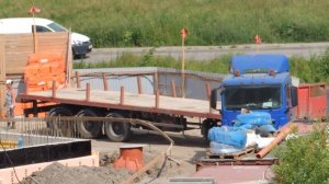 Грузовик с полуприцепом едет задним ходом по очень узкой дорожке.